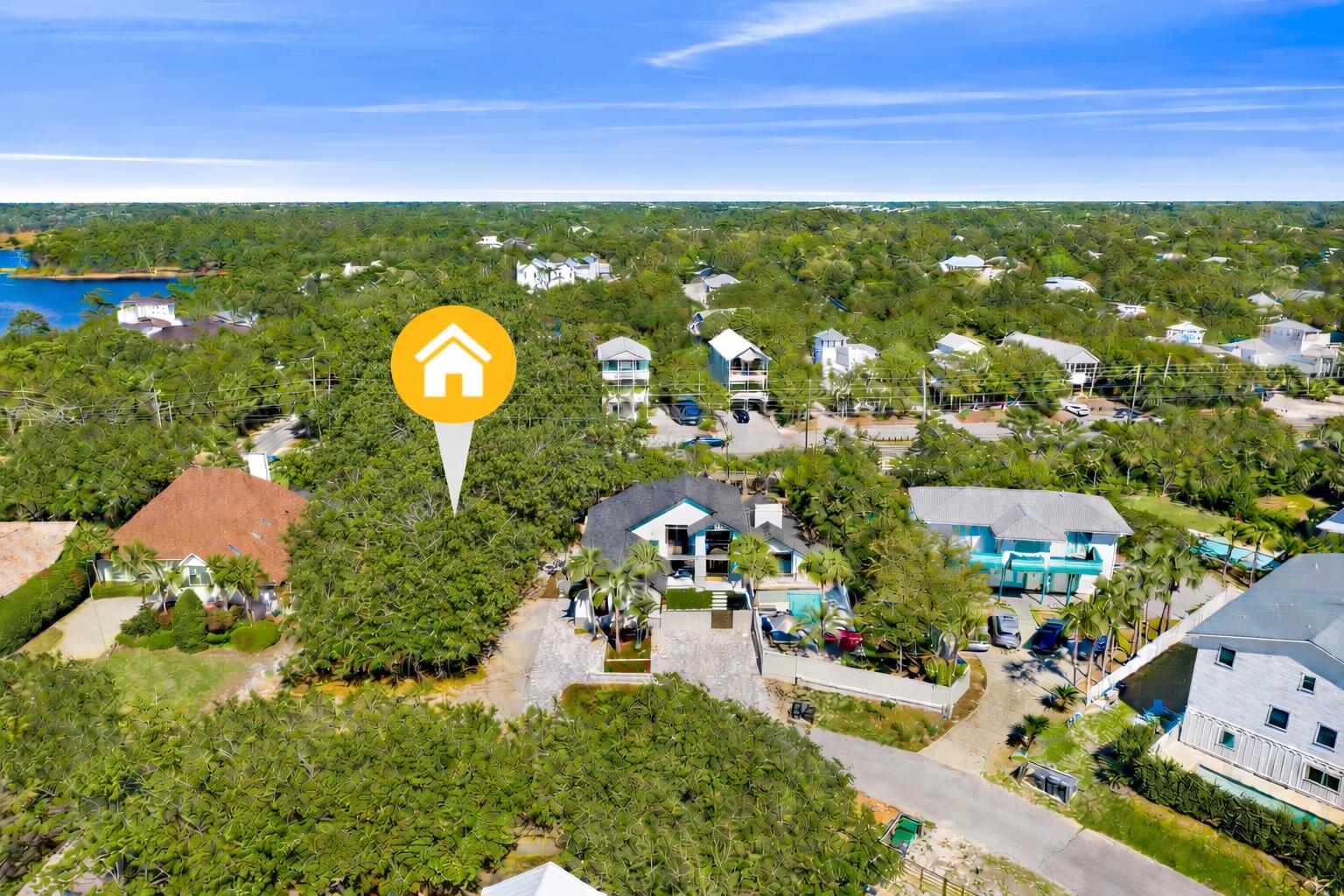 Aerial neighborhood view with a yellow marker pointing to a wooded lot among coastal homes.