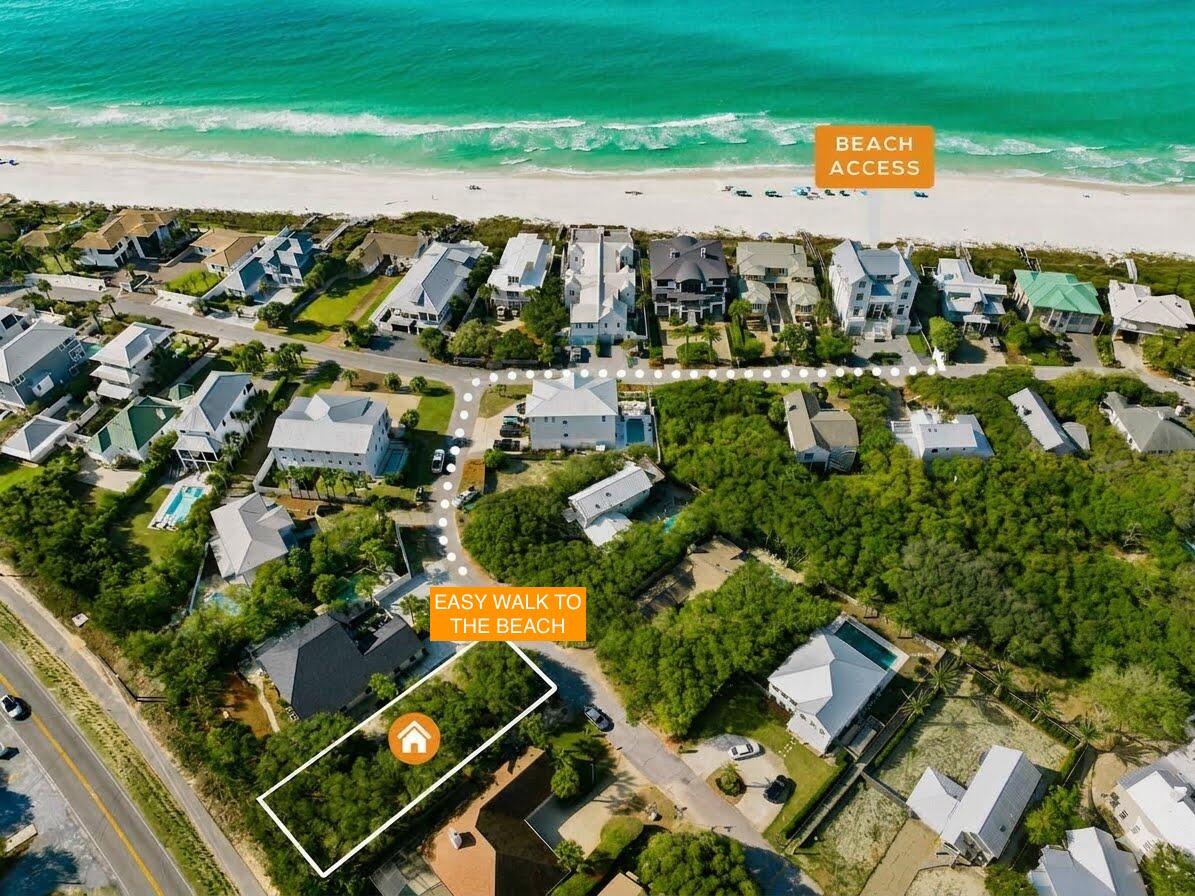 Outlined wooded lot near beachside homes, with the beach and turquoise water beyond.