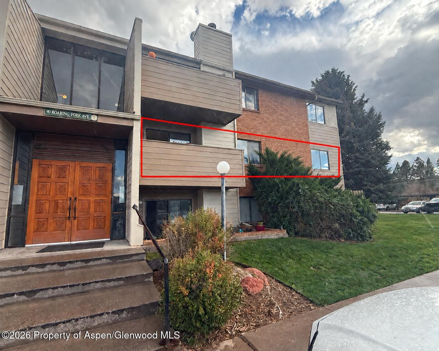 Residential unit outlined in red on a multi-unit building, with a balcony and brick façade.