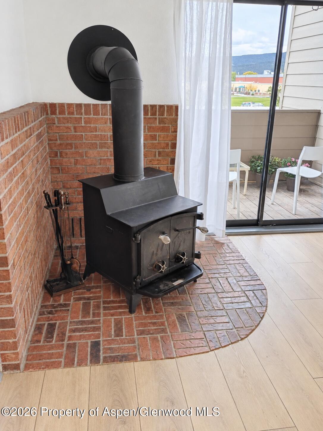 Black wood-burning stove beside a sliding glass door opening onto a balcony with mountain views.