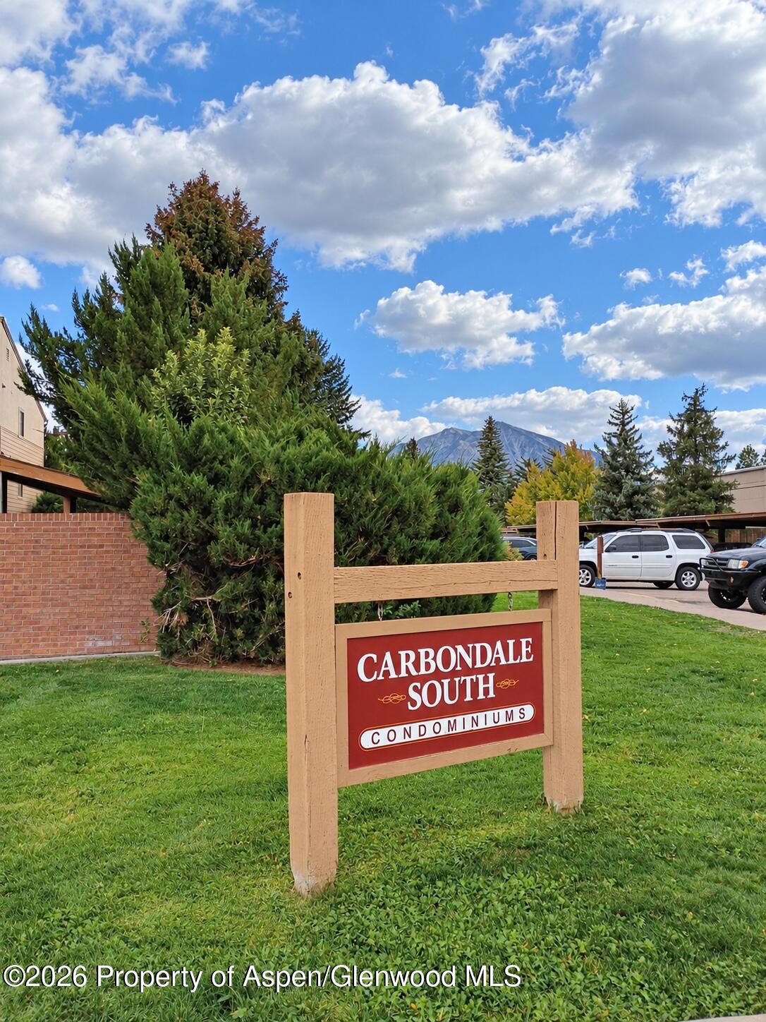 Carbondale South Condominiums entrance sign beside landscaped grounds, with a mountain visible in the distance.