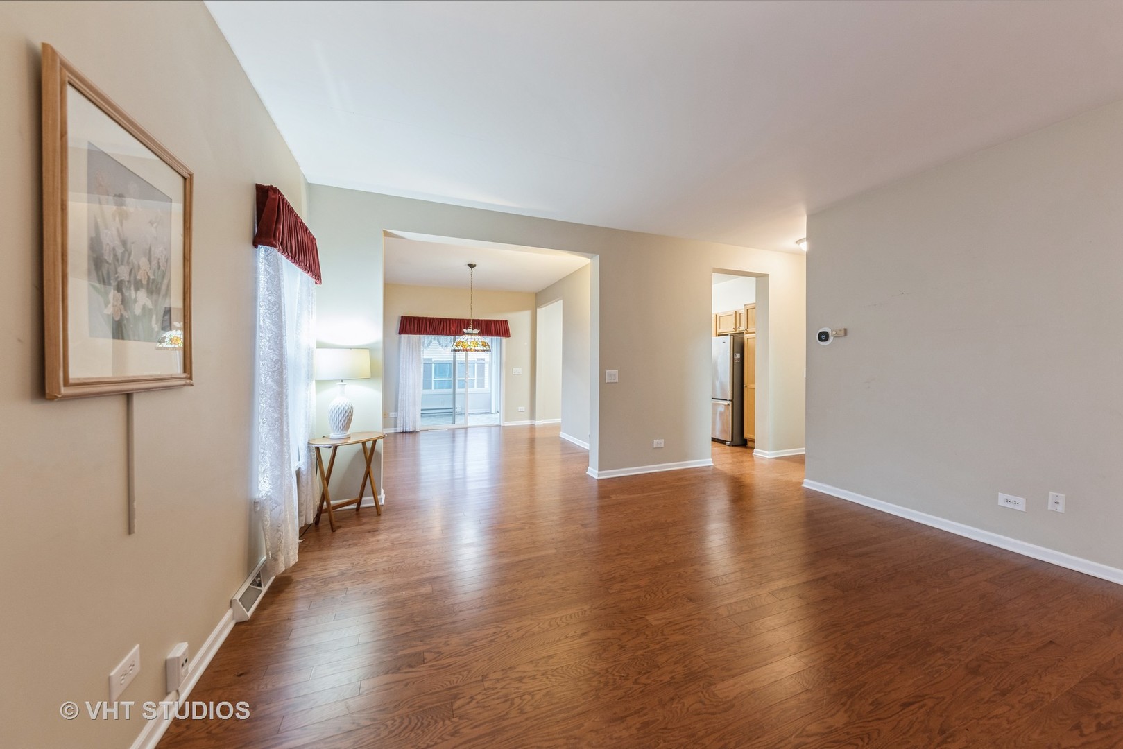 Living room with hardwood floors, an open dining area, and a glimpse of the kitchen.