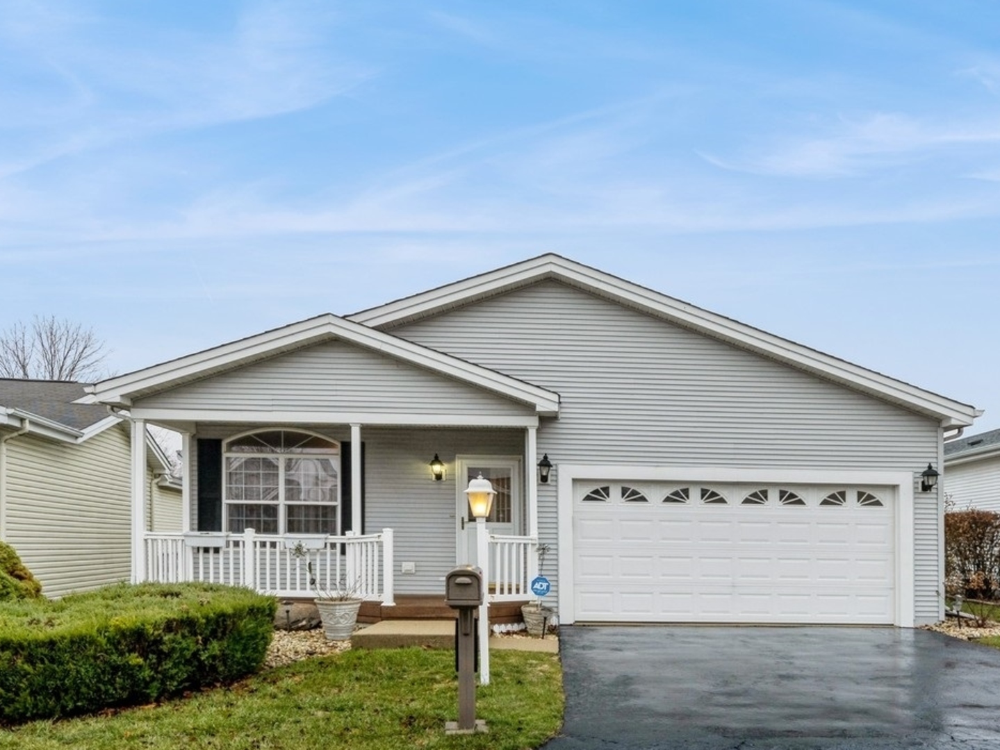 Light gray home with a covered porch, white railings, and an attached two-car garage.