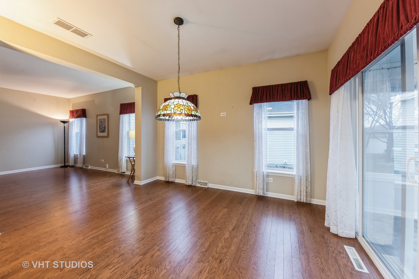 Empty dining area with hardwood floors, a stained-glass pendant light, and a sliding glass door.