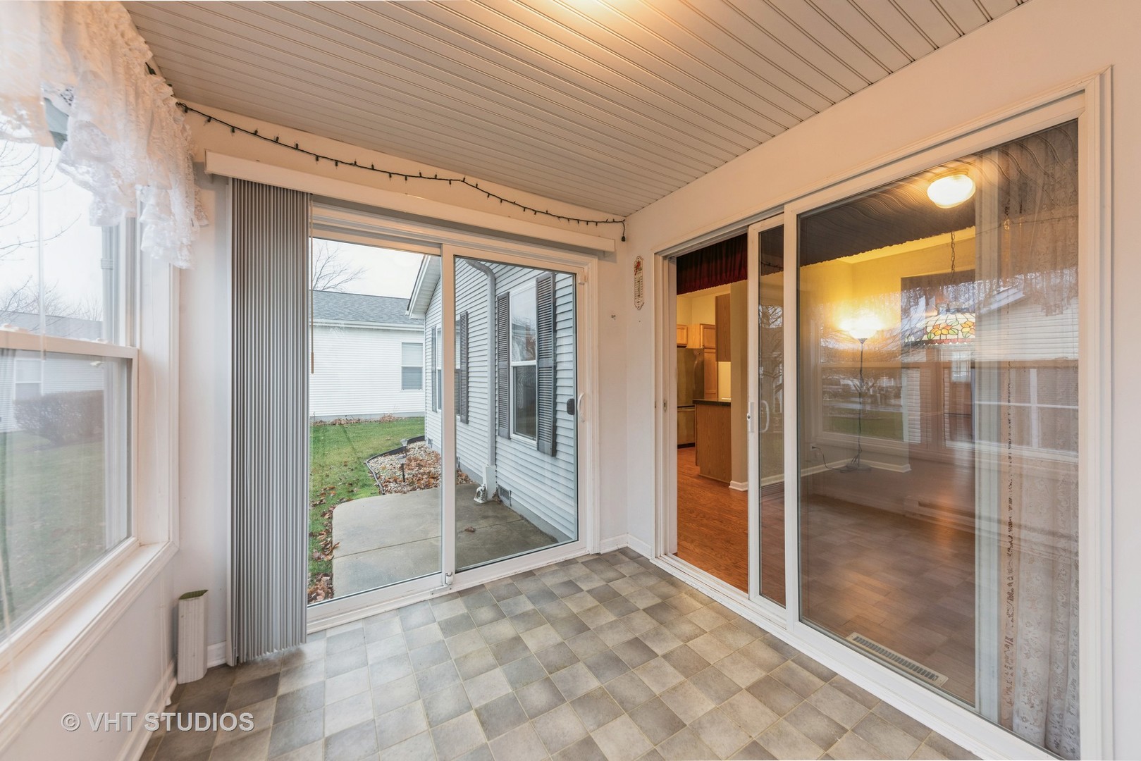 Enclosed sunroom with checkerboard tile flooring and sliding glass doors to a backyard patio.