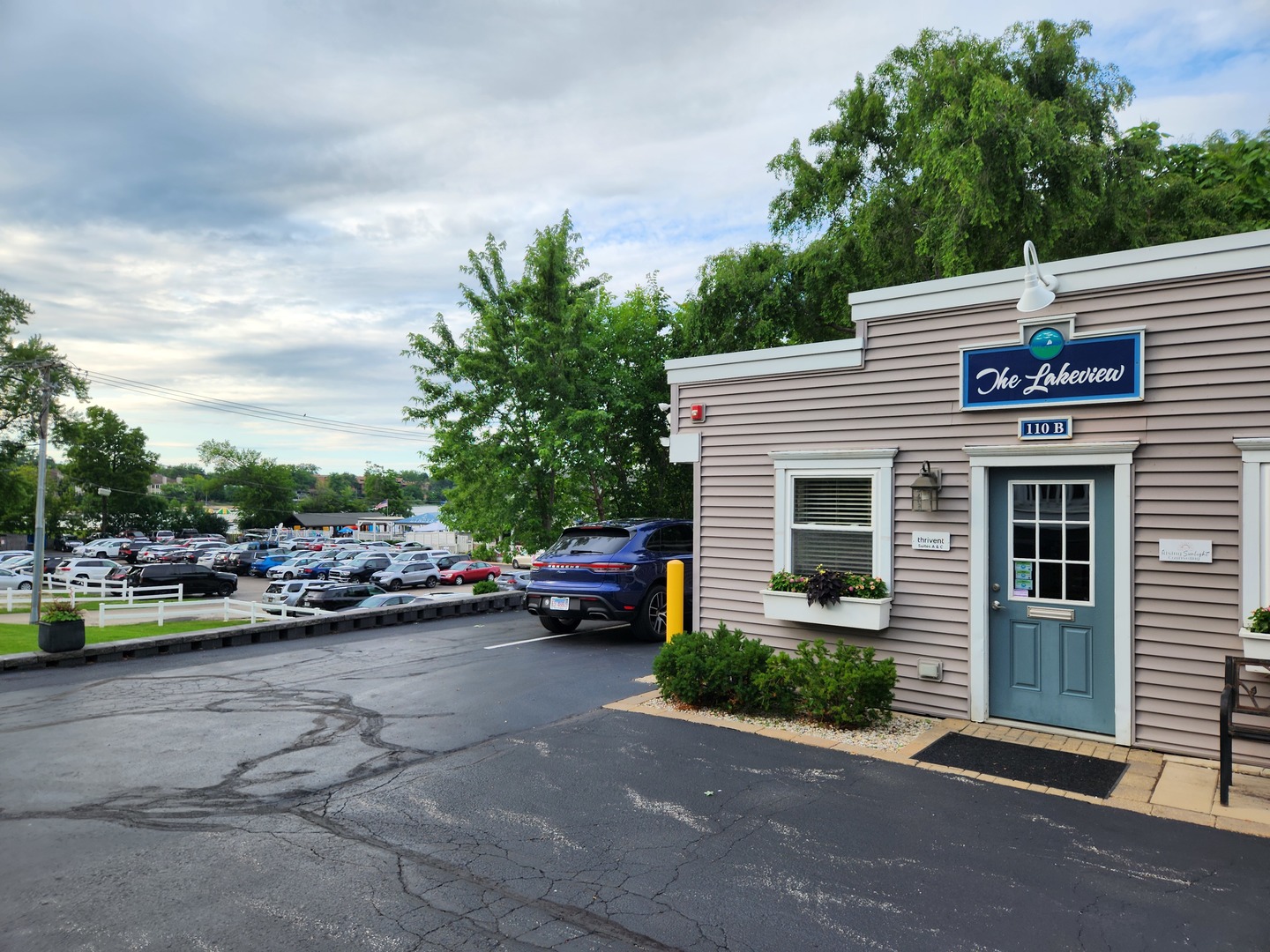 Commercial building with The Lakeview sign, teal door, flower boxes, and a crowded parking lot.