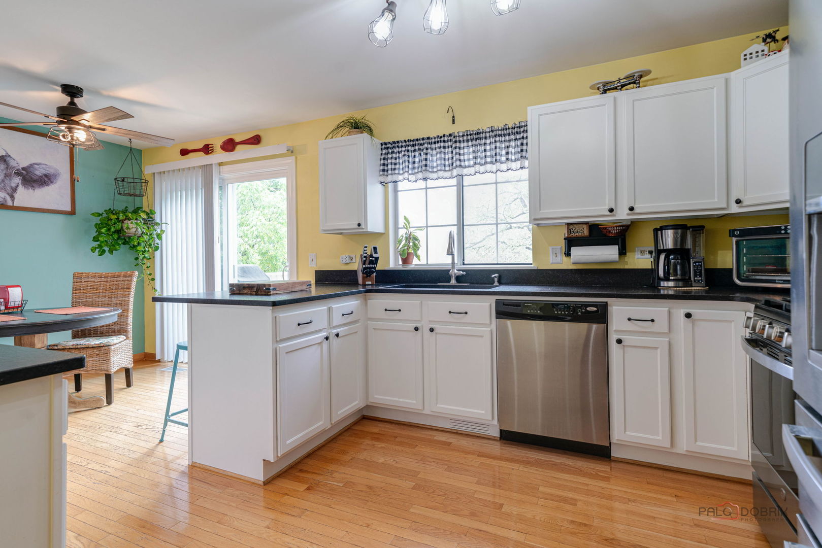 Kitchen with white cabinets, dark countertops, stainless steel appliances, and hardwood floors.
