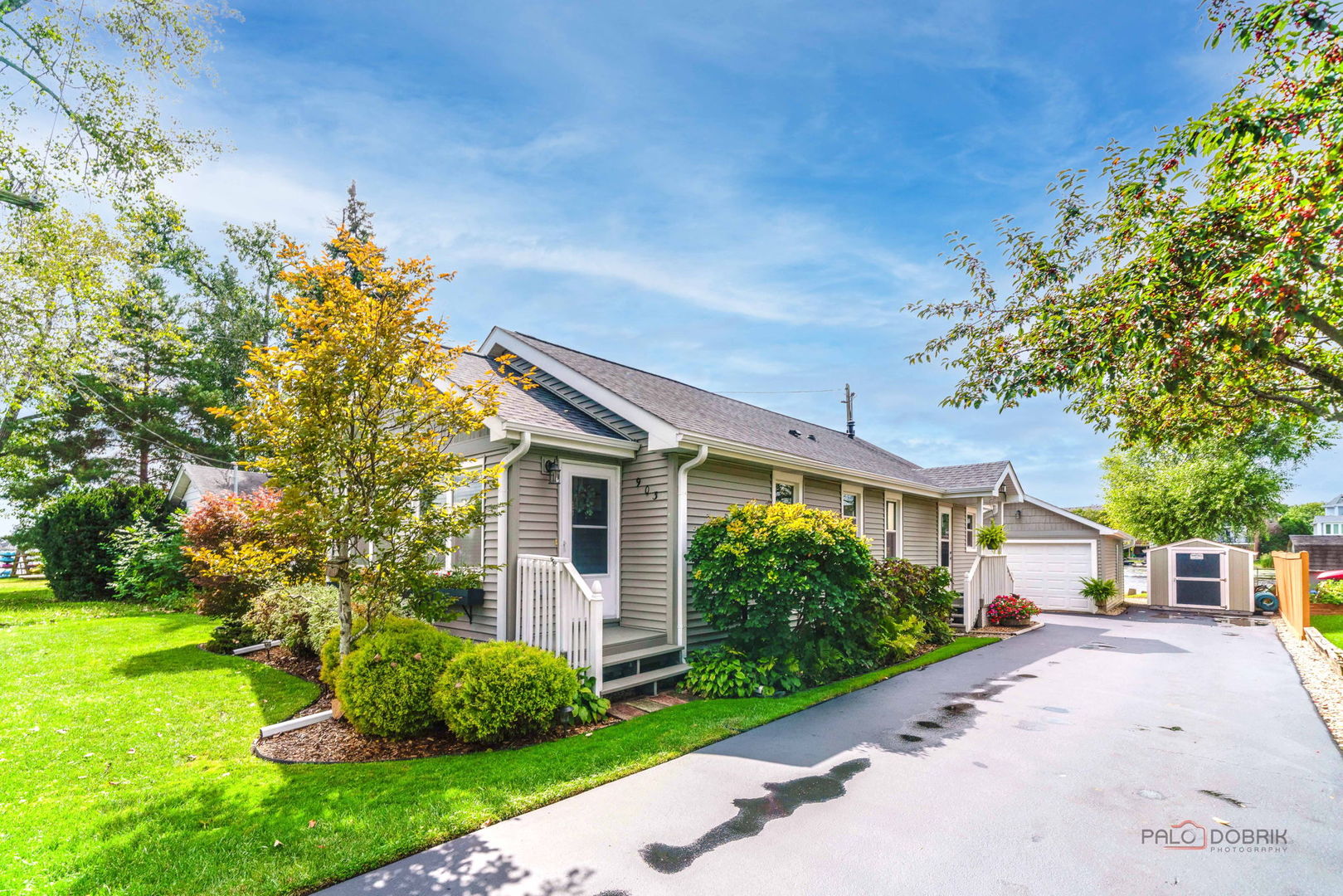 Single-story gray home with a front porch, landscaped garden, and attached garage.
