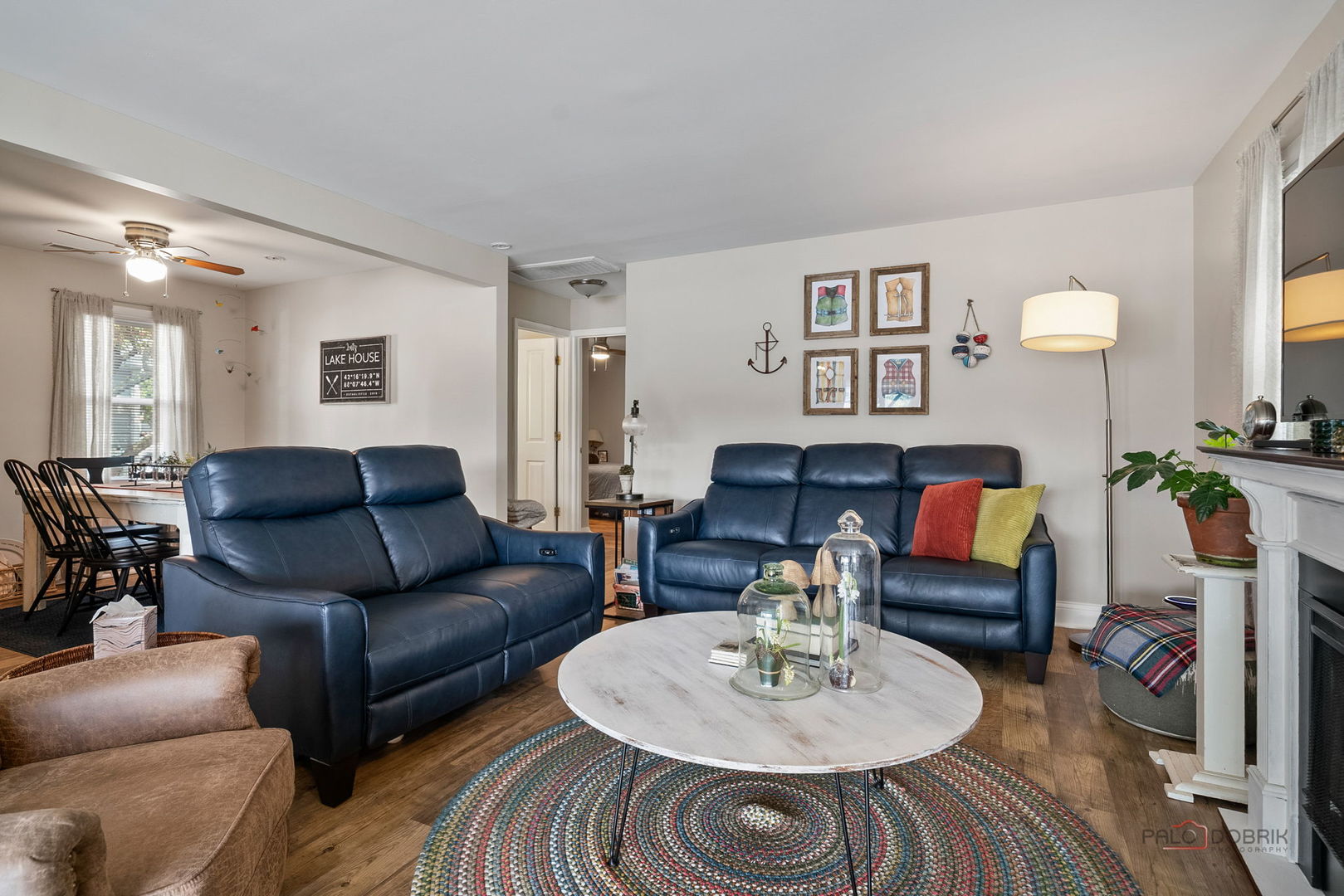 Living room with navy leather sofas, a round coffee table, colorful braided rug, and white fireplace.