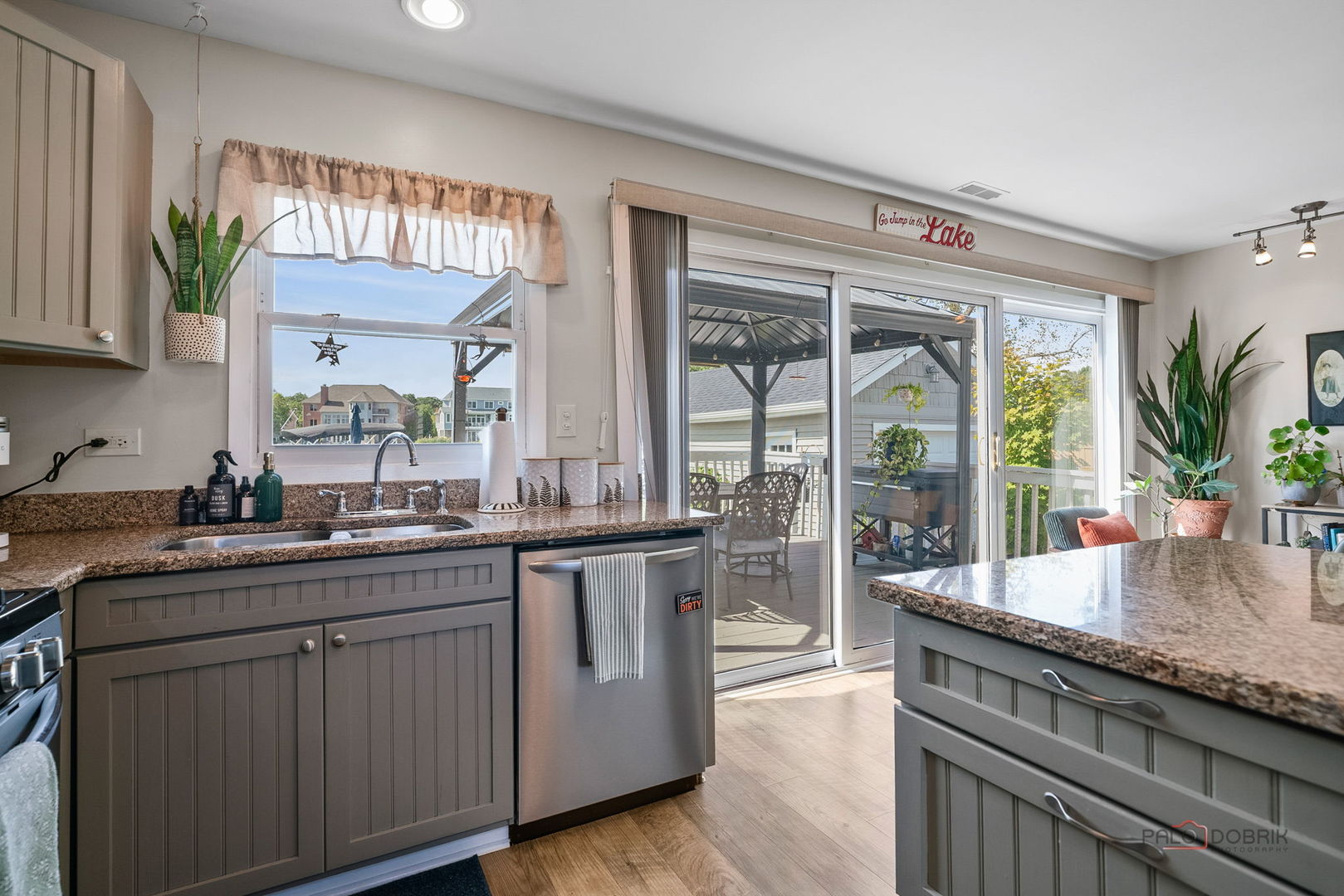 Kitchen with gray cabinets, granite counters, an island, and sliding doors to a covered deck.