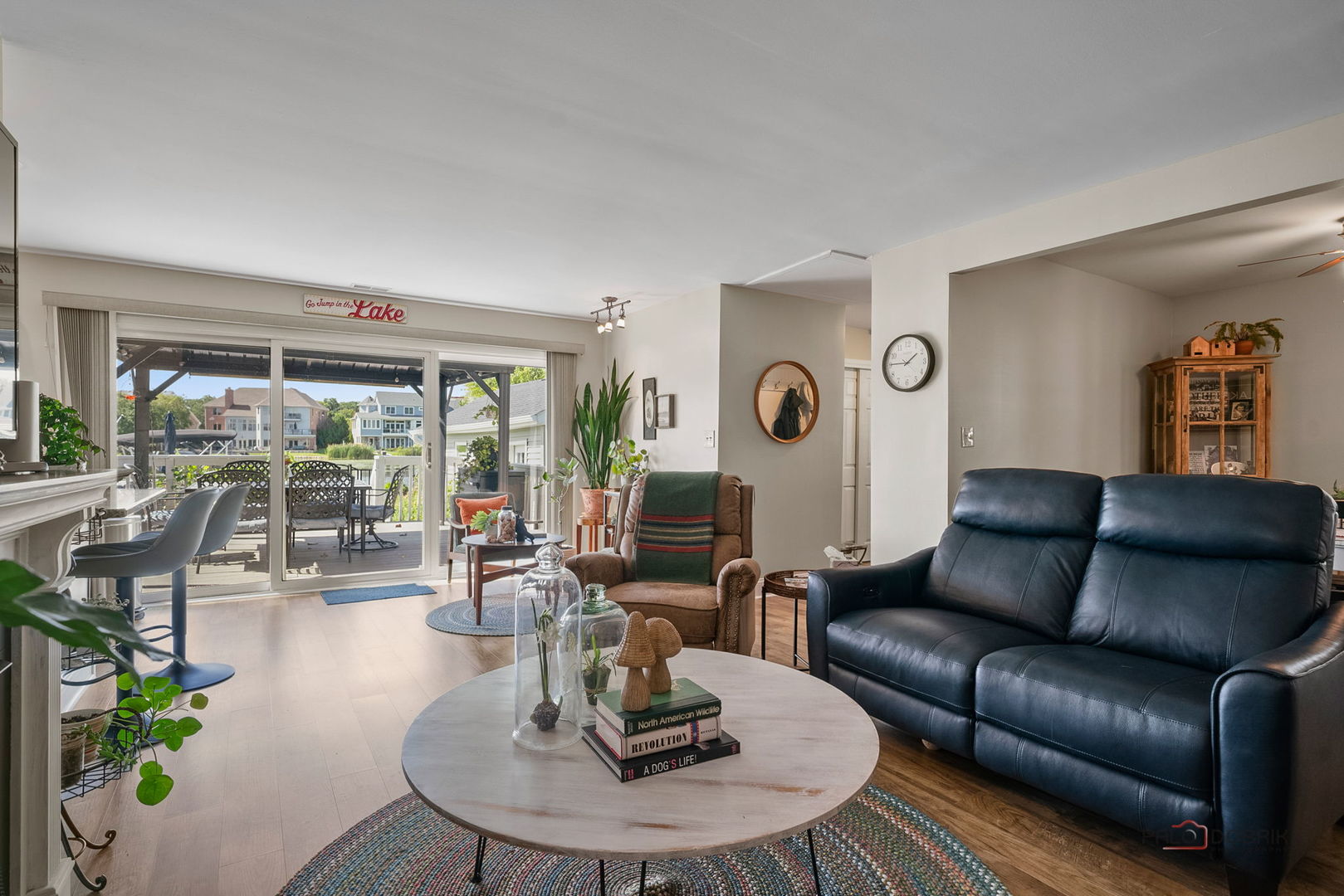Living room with a blue leather sofa and sliding glass doors opening onto a furnished deck.
