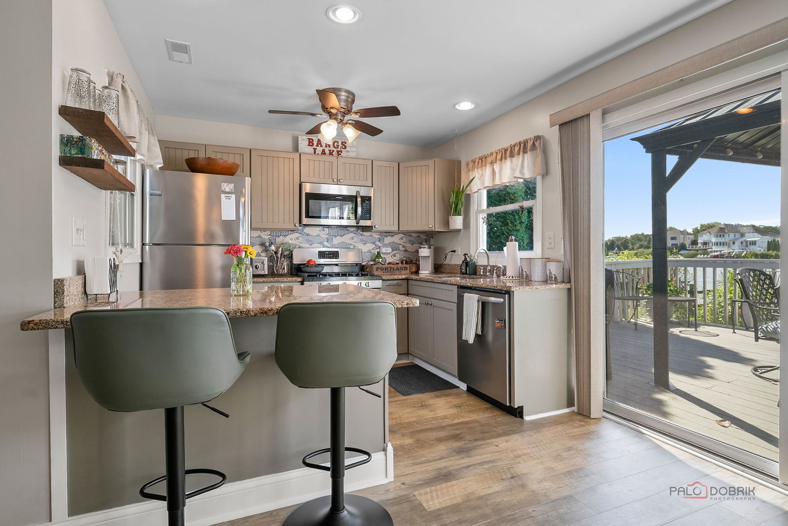 Kitchen with granite island, stainless appliances, and sliding doors opening to a lakefront deck.