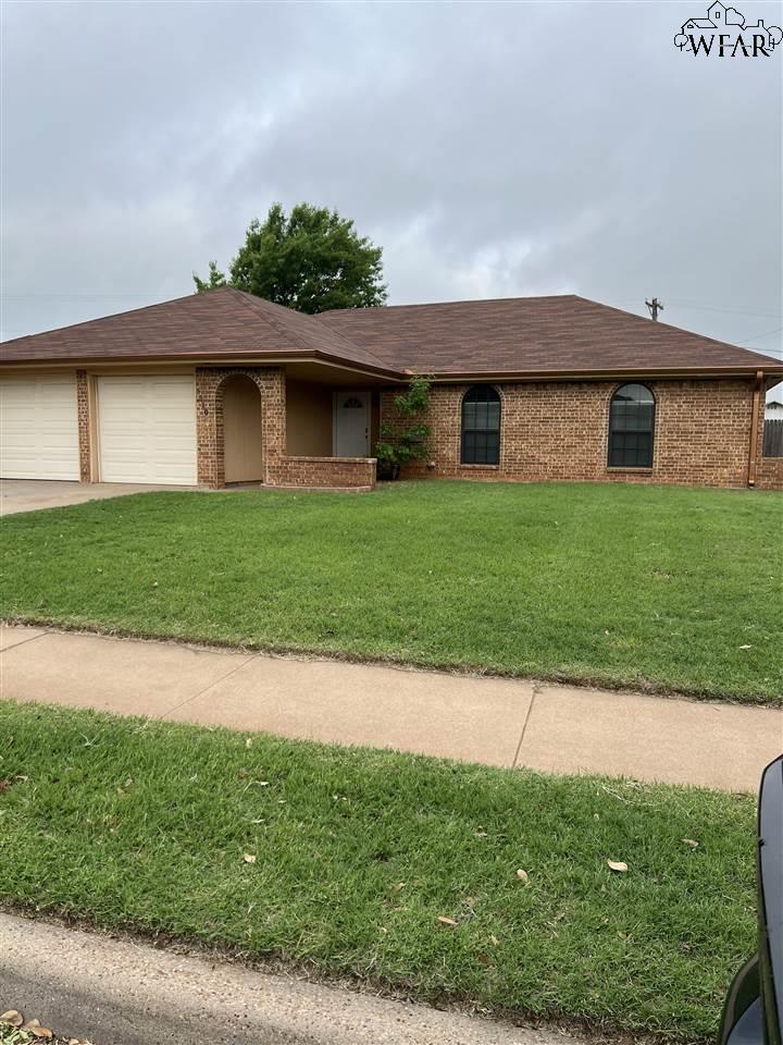 Single-story brick house with an attached garage, arched entryway, and broad front lawn.
