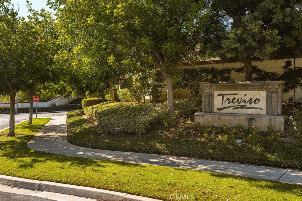 Treviso community entrance sign beside a tree-lined sidewalk and landscaped lawn.