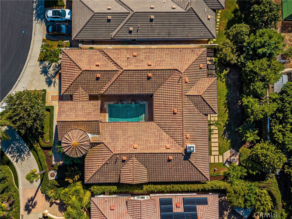 Aerial view of a tiled-roof home with a central swimming pool and landscaped yard.