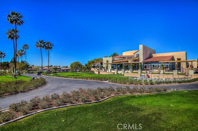 Tan community building with red-tile awnings, palm trees, and landscaped grounds.
