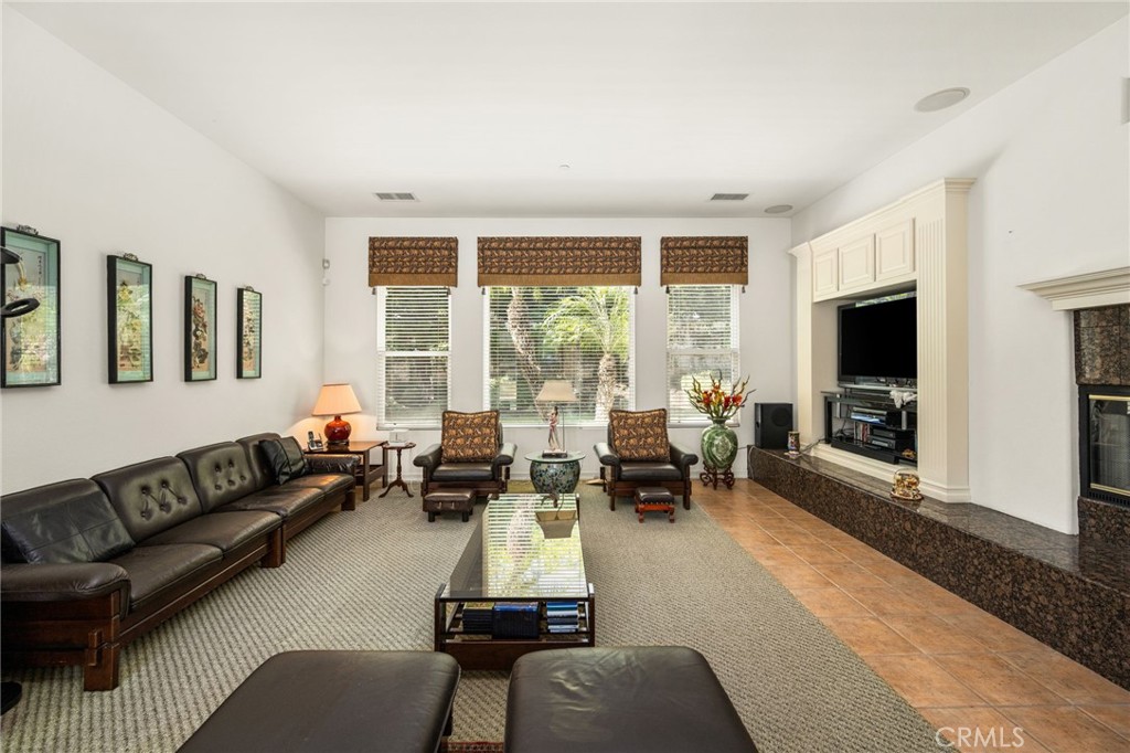 Living room with leather seating, three large windows, and a built-in entertainment center.