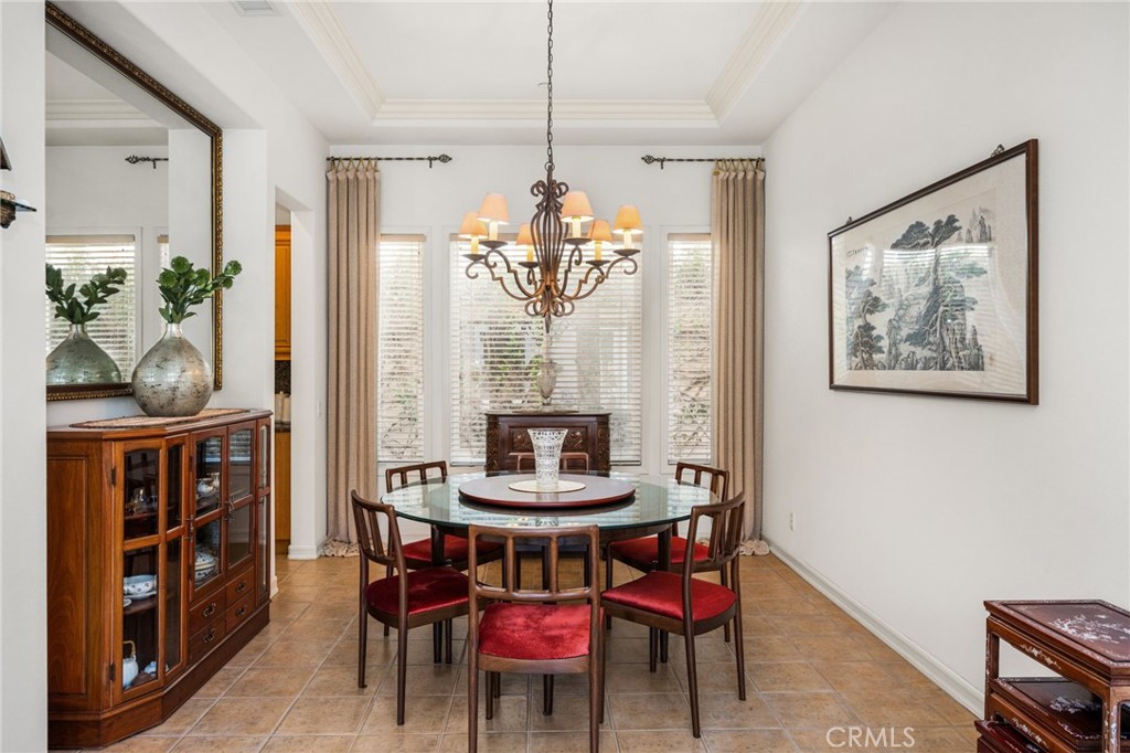 Furnished dining room with a round glass table, red-upholstered chairs, and a decorative chandelier.