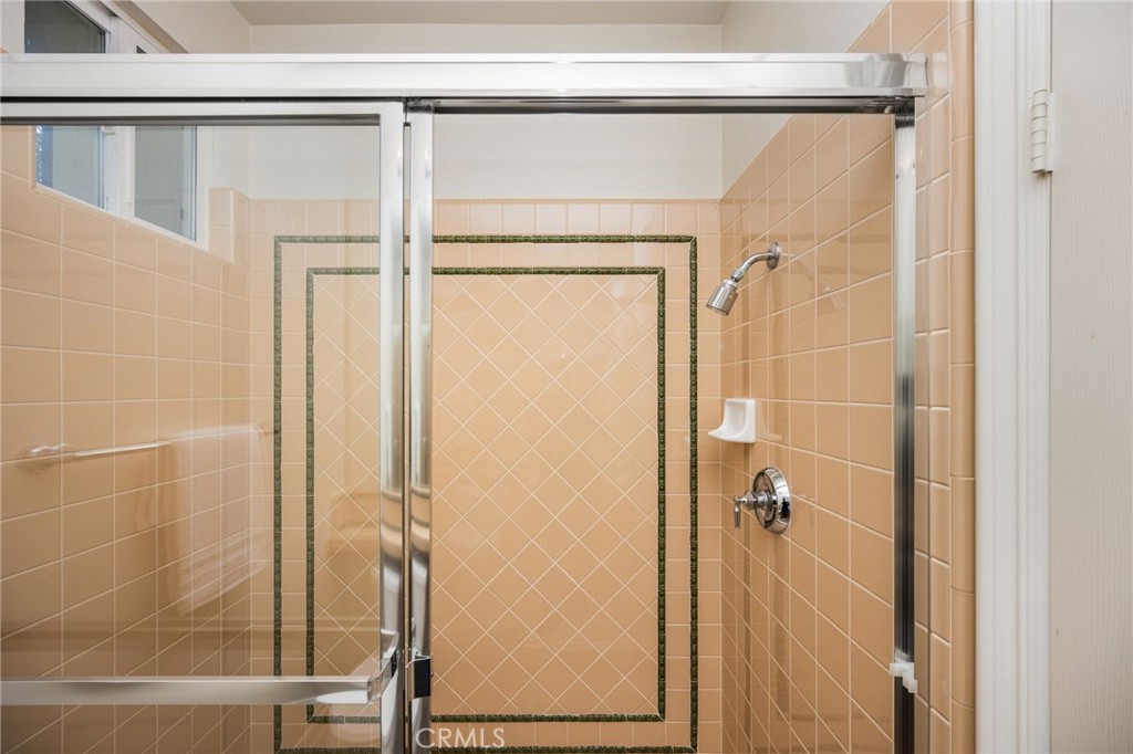 Tiled shower with glass doors and a dark decorative tile border.