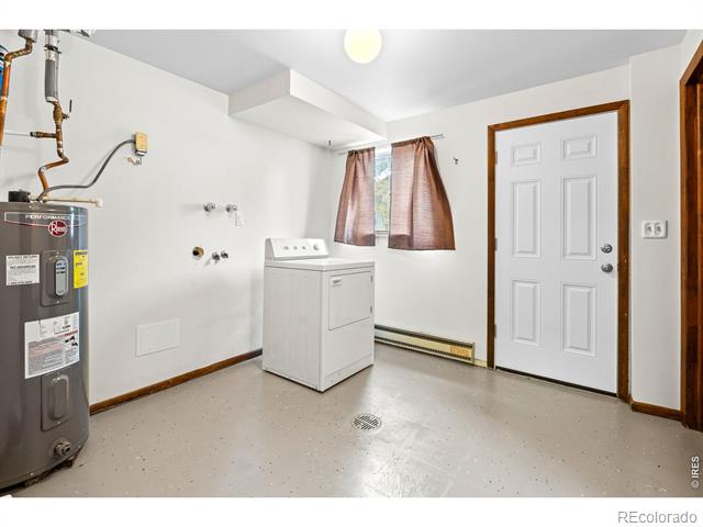 Utility laundry room with a water heater, laundry appliance, exposed plumbing, and floor drain.