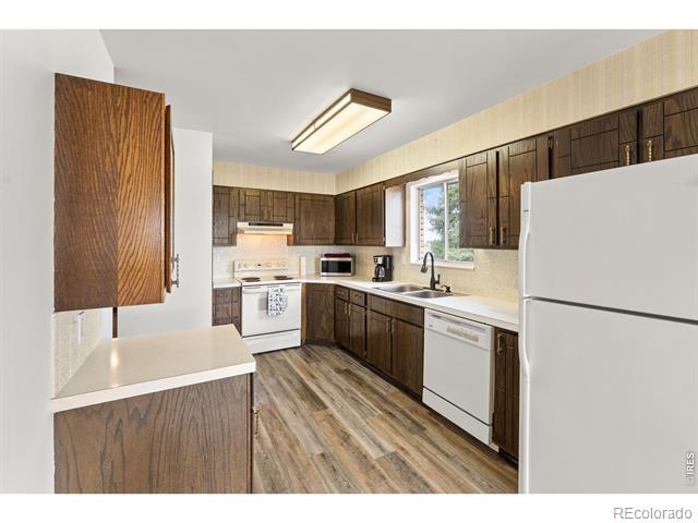 Kitchen with dark wood cabinets, white countertops, and a window above the sink.