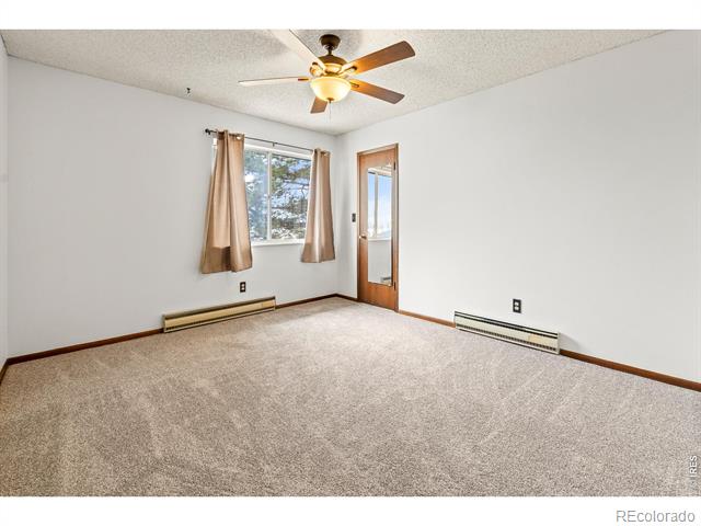 Empty bedroom with beige carpet, tan curtains, and a wood-framed glass door.