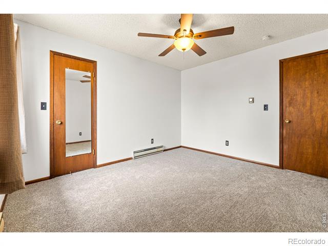 Vacant bedroom with a mirrored closet door, ceiling fan, and light carpet.