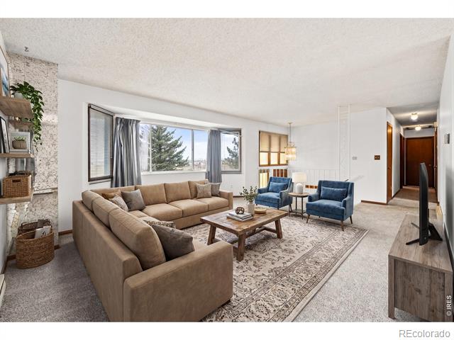 Living room with a tan sectional, blue armchairs, patterned rug, and stone fireplace.