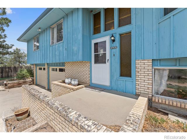 Blue-sided home with a white front door, brick porch, and garage.