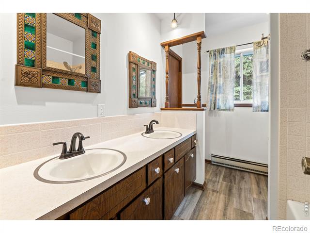 Bathroom with a double-sink vanity, decorative mirrors, and a curtained window.