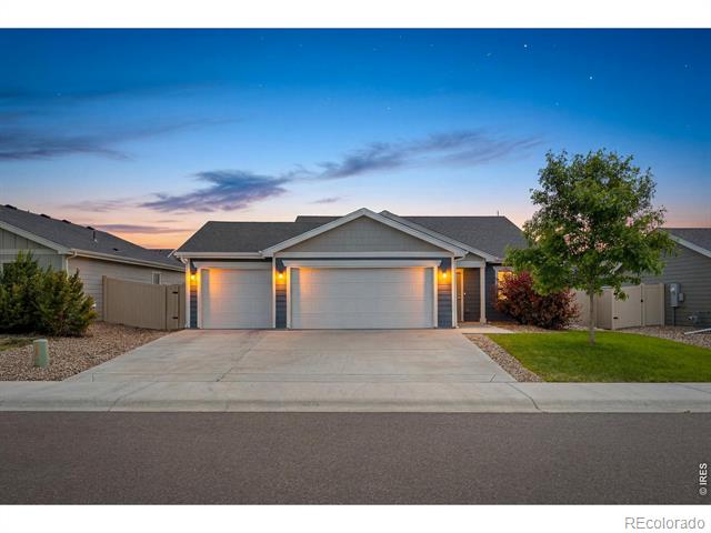 Gray home with a two-car garage and wide driveway at dusk.