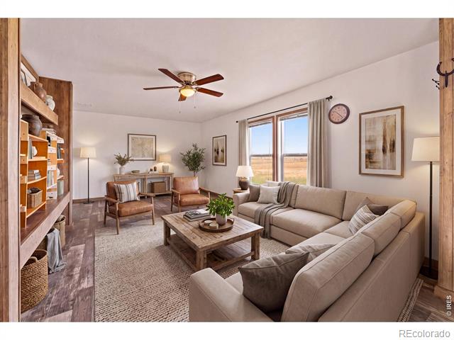 Living room with a beige sectional, wood coffee table, and window overlooking open countryside.