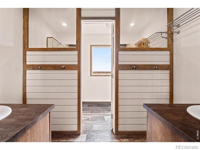 Bathroom with two wood-framed vanities and a doorway between them.