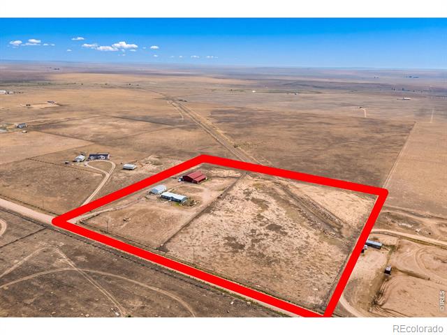 Aerial view of a rural parcel outlined in red, with a few buildings and dirt access roads.