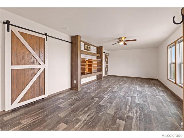 Spacious empty room with gray flooring, built-in shelves, and a sliding barn door.