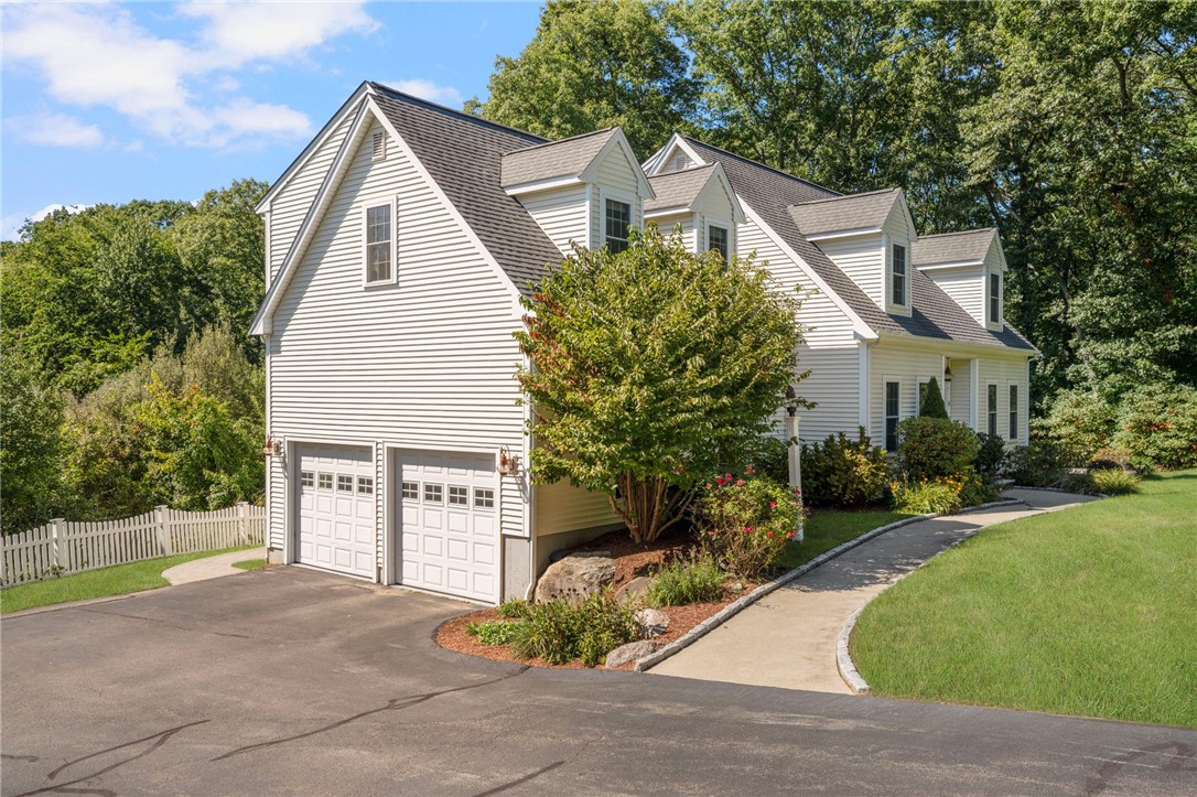 White multi-gabled house with an attached double garage, curved walkway, and landscaped front lawn.