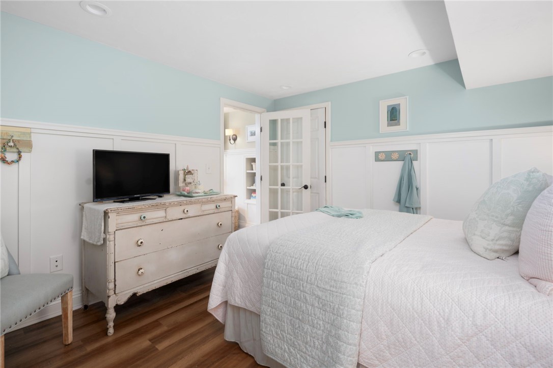 Bedroom with a white quilted bed, pale aqua walls, and a vintage dresser topped with a television.