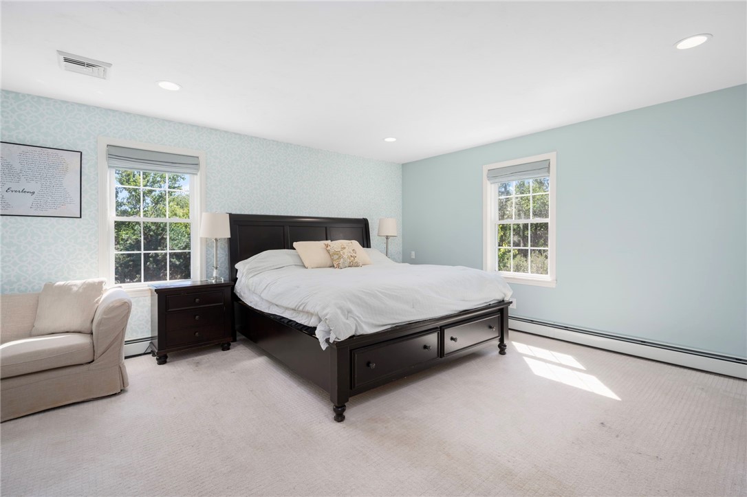 Bedroom with a dark wood bed, pale blue walls, patterned wallpaper, and two windows.