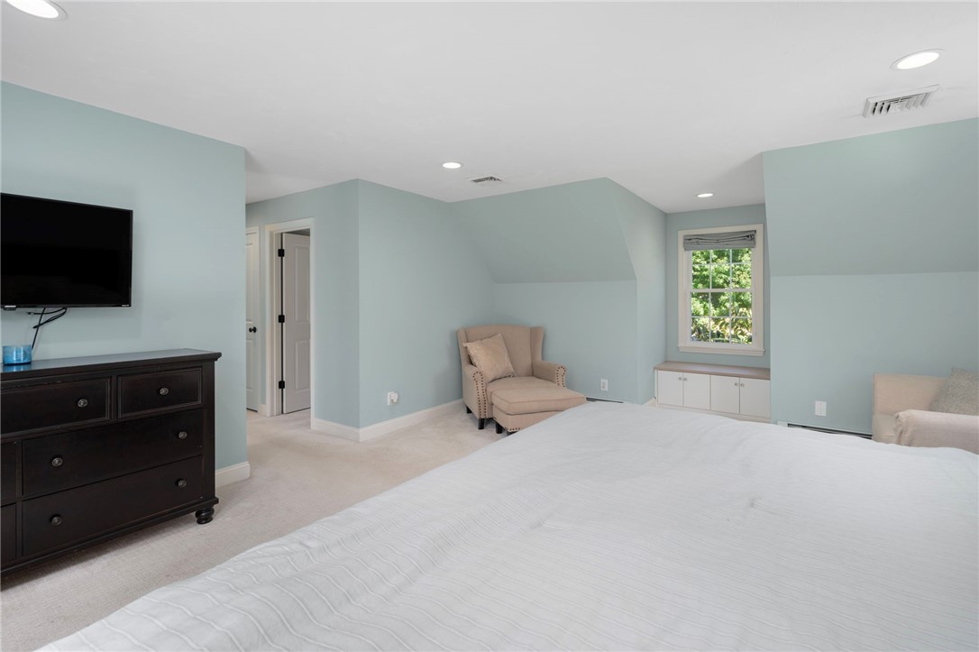 Bedroom with a white bed, pale blue walls, and a window-side seating area.