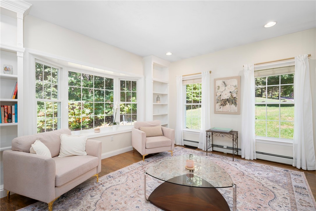 Bright living room with large divided-light windows, pale sofas, and a patterned area rug.