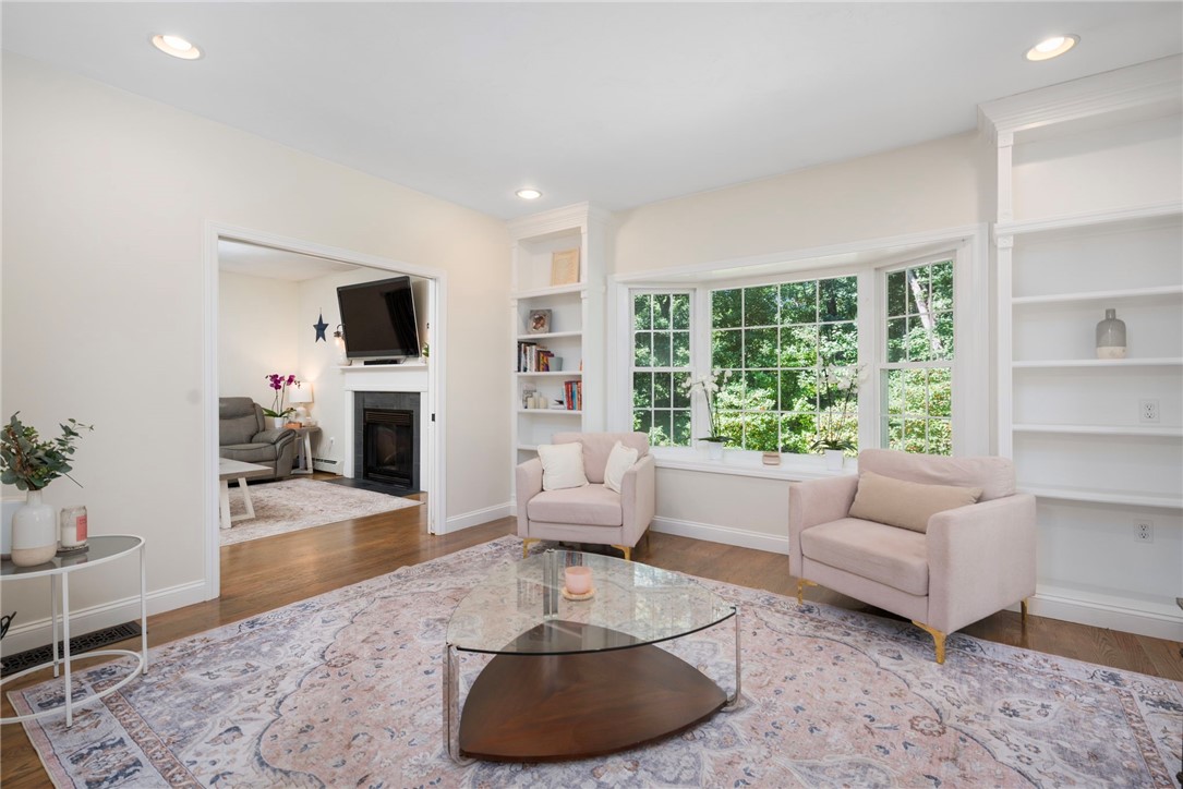 Living room with two blush armchairs, built-in shelving, and a large garden-facing window.