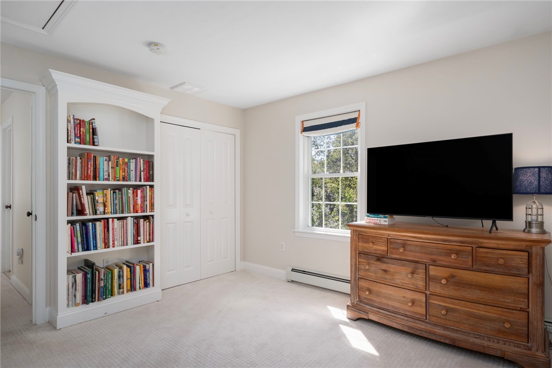 Bedroom with a built-in bookcase, double closet, and television on a wooden dresser.