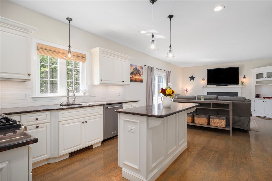 Bright white kitchen with a large island opening to a furnished living room.