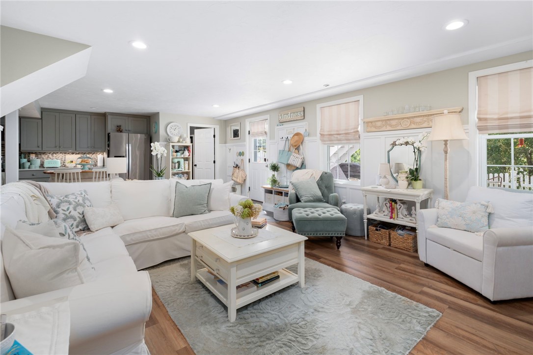 Living room with white sofas, a teal accent chair, and an open kitchen.