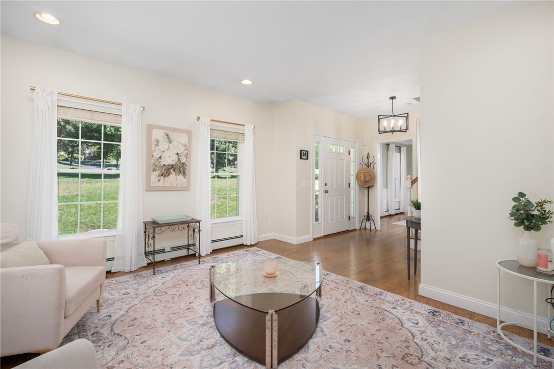 Living room with large curtained windows, a patterned rug, and a view toward the front entry.