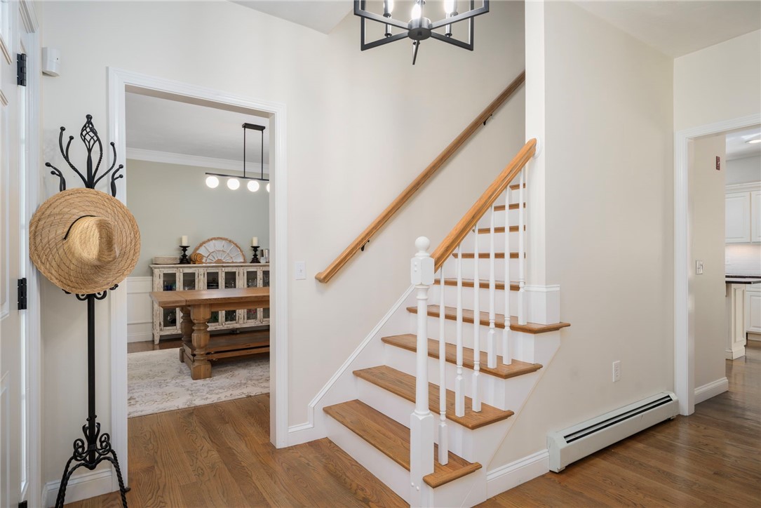 Entryway with a wood-tread staircase, white balusters, and an adjoining dining room.