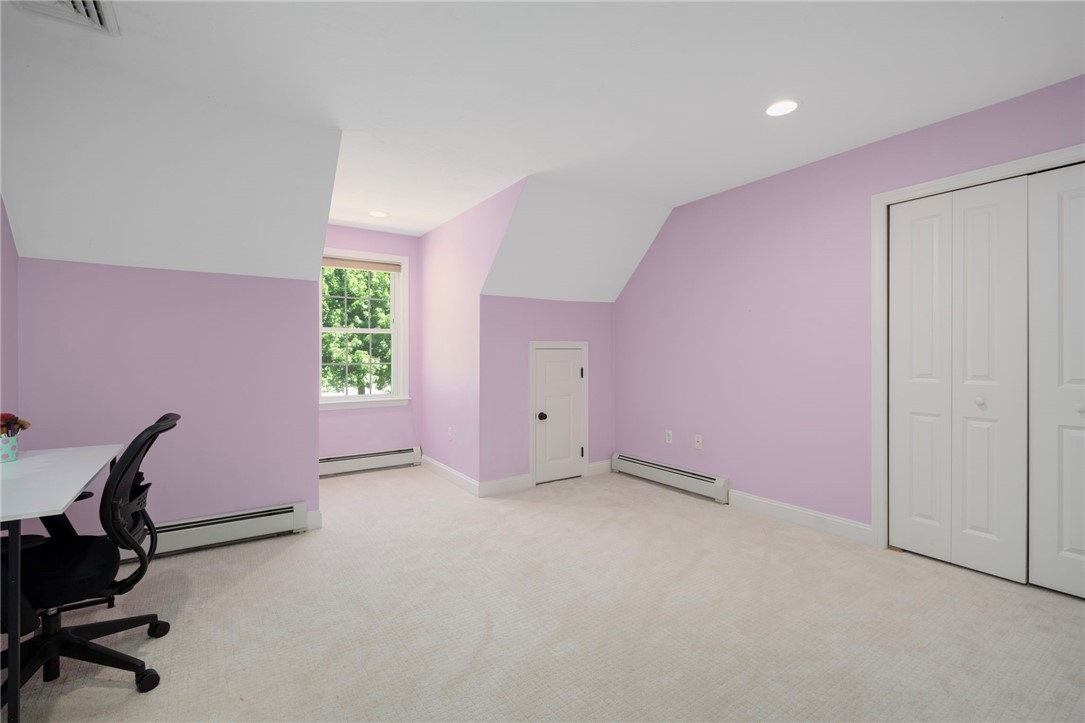 Bedroom with lavender walls, sloped ceiling, carpet, and a small built-in door.