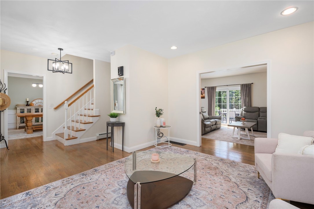 Living room with a glass coffee table, patterned rug, and staircase beside an adjoining sitting room.