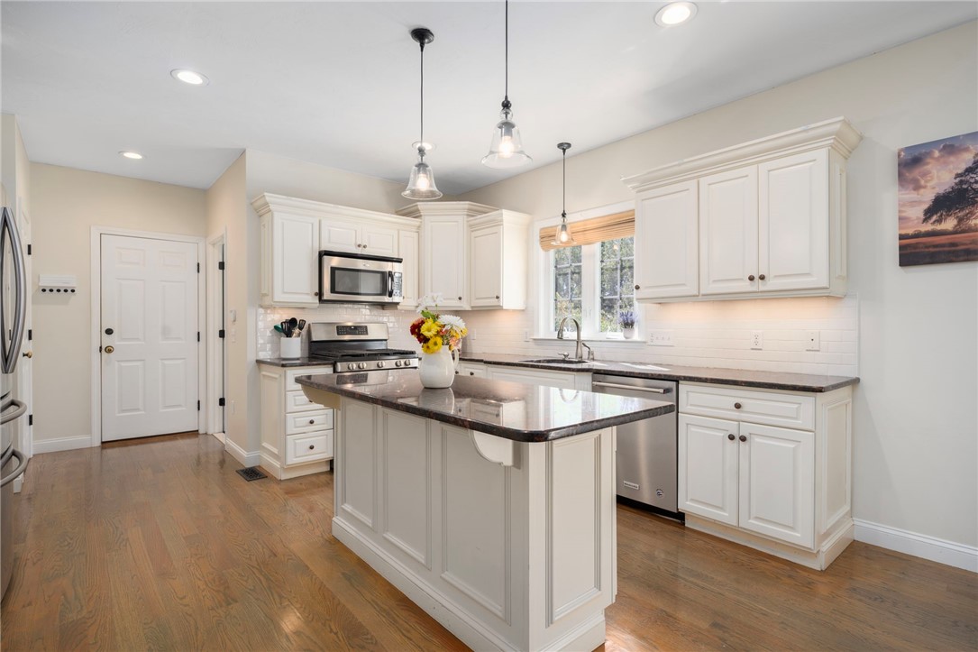Bright kitchen with white cabinetry, a dark stone island, and stainless steel appliances.