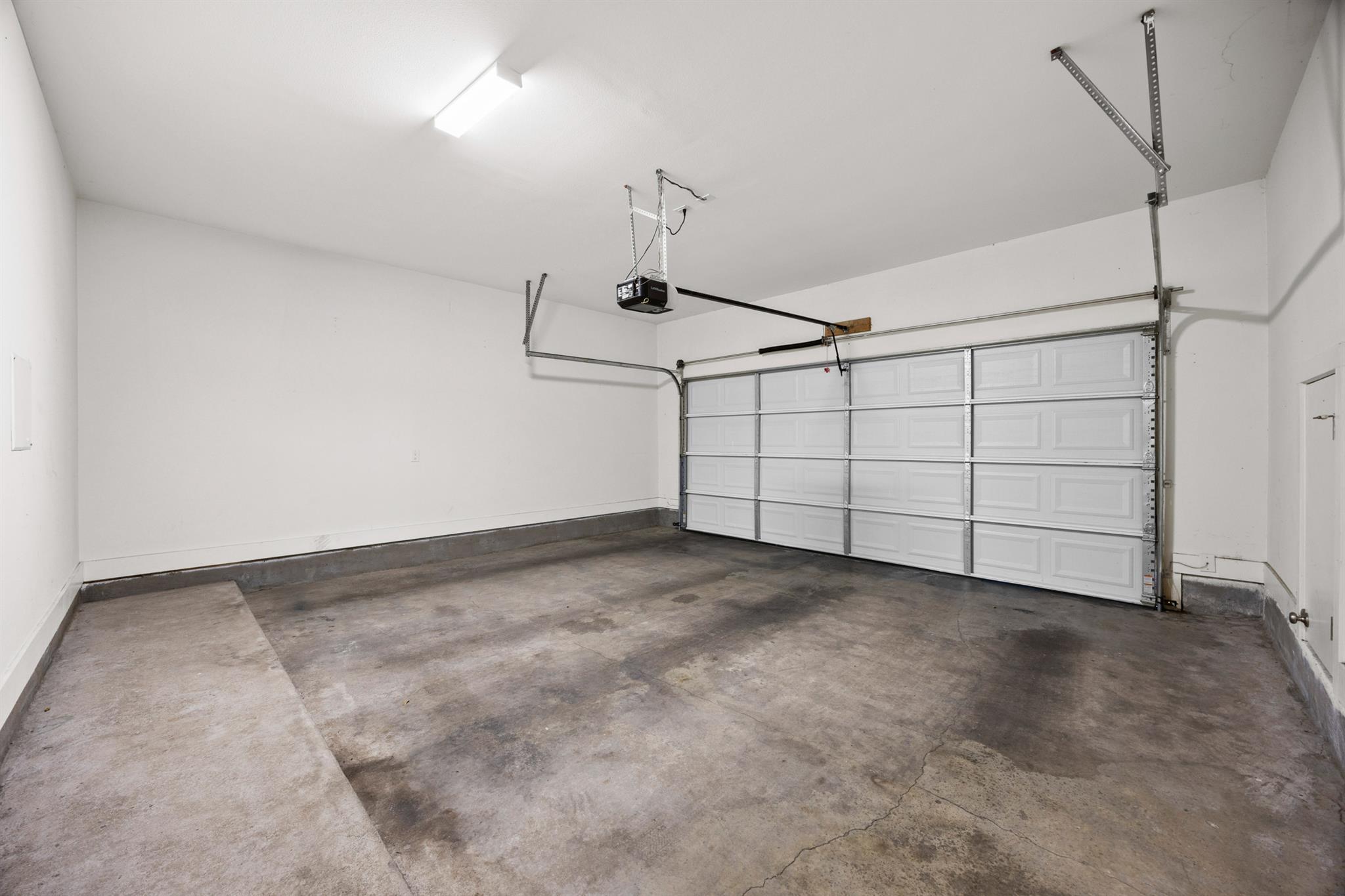 Vacant garage with a cracked concrete floor and closed sectional door.